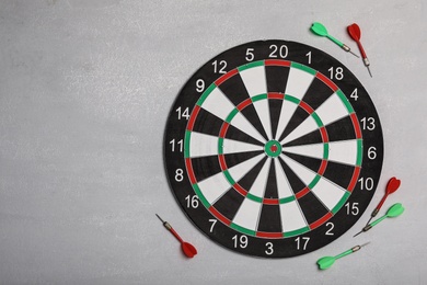 Dart board with color arrows on light stone background, top view. Space for text