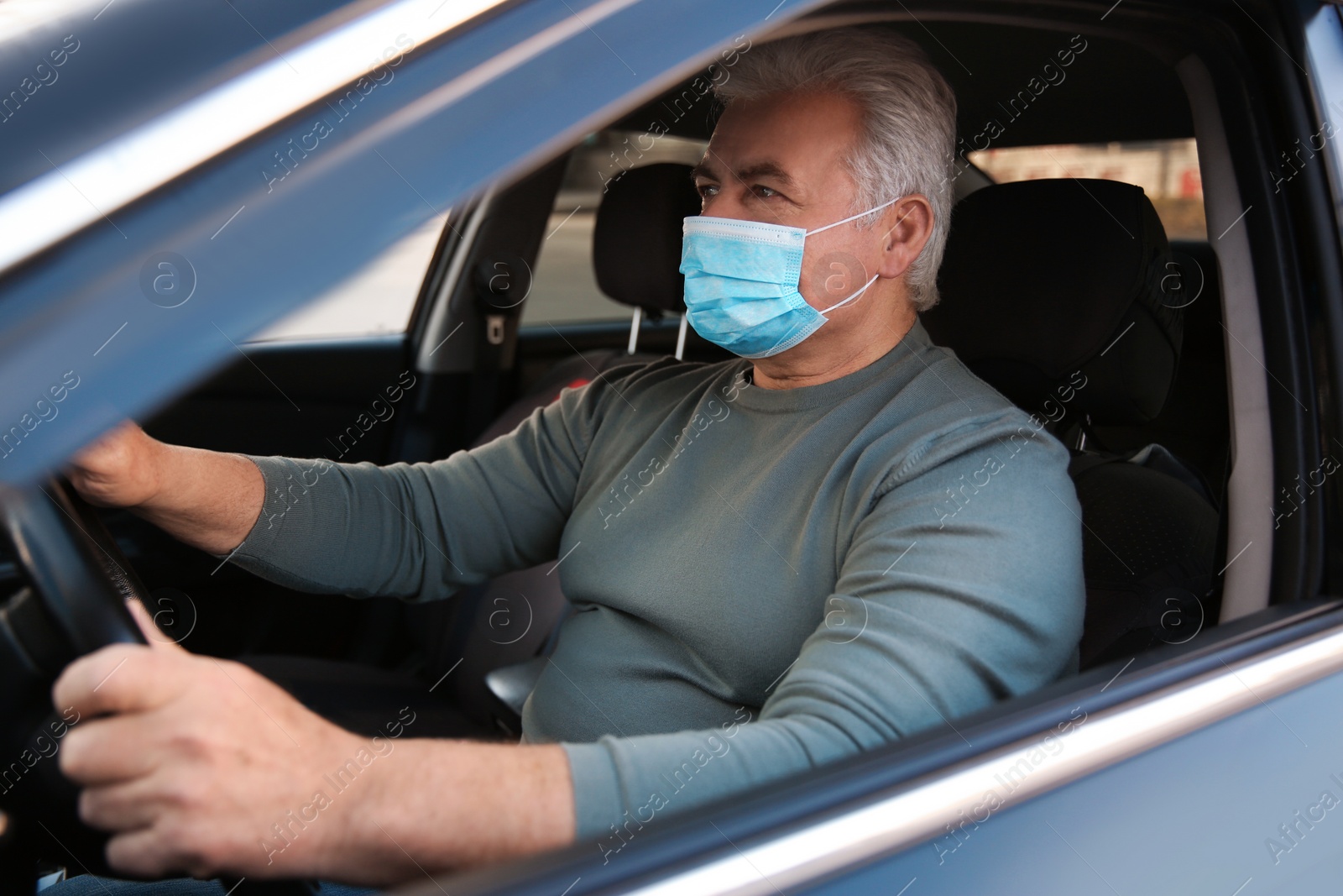 Photo of Senior man with medical mask in car. Virus protection