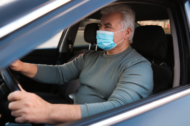 Photo of Senior man with medical mask in car. Virus protection