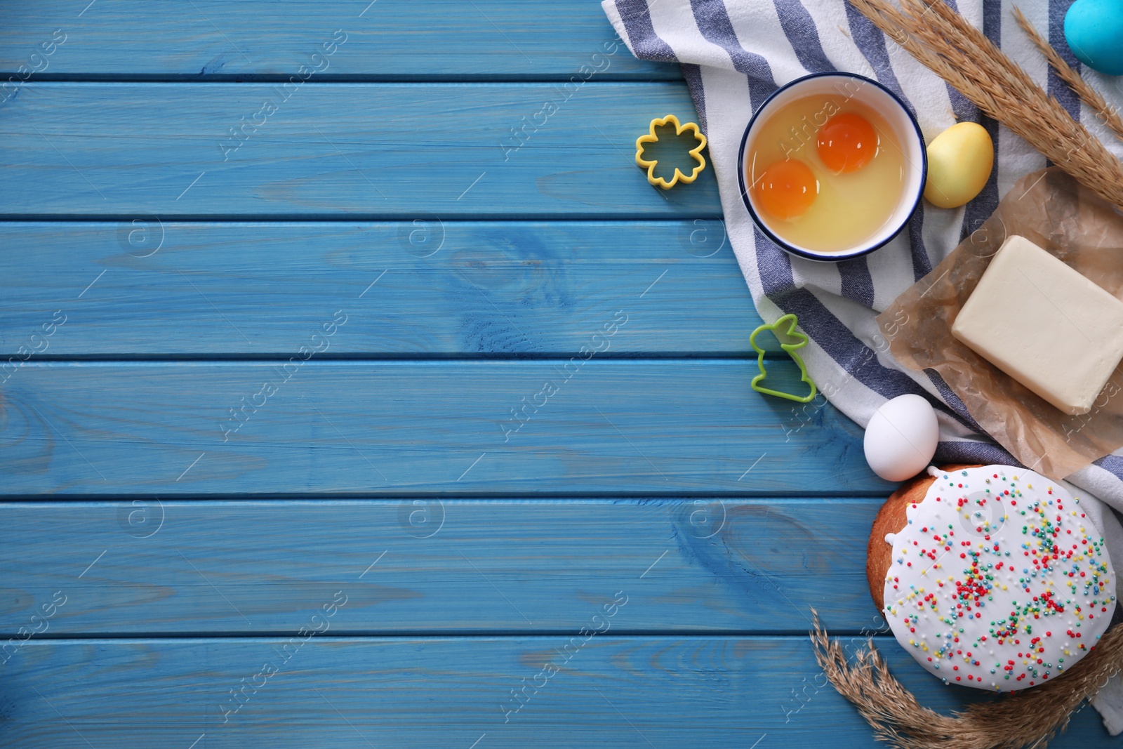 Photo of Flat lay composition with Easter cake and ingredients on blue wooden table. Space for text