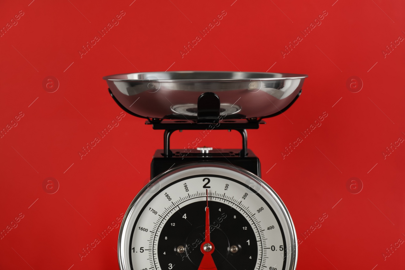 Photo of Retro mechanical kitchen scale on red background, closeup