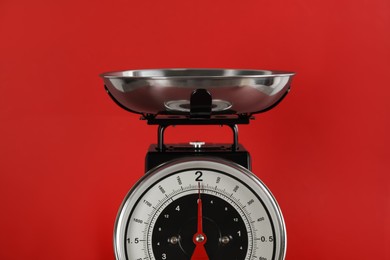 Photo of Retro mechanical kitchen scale on red background, closeup