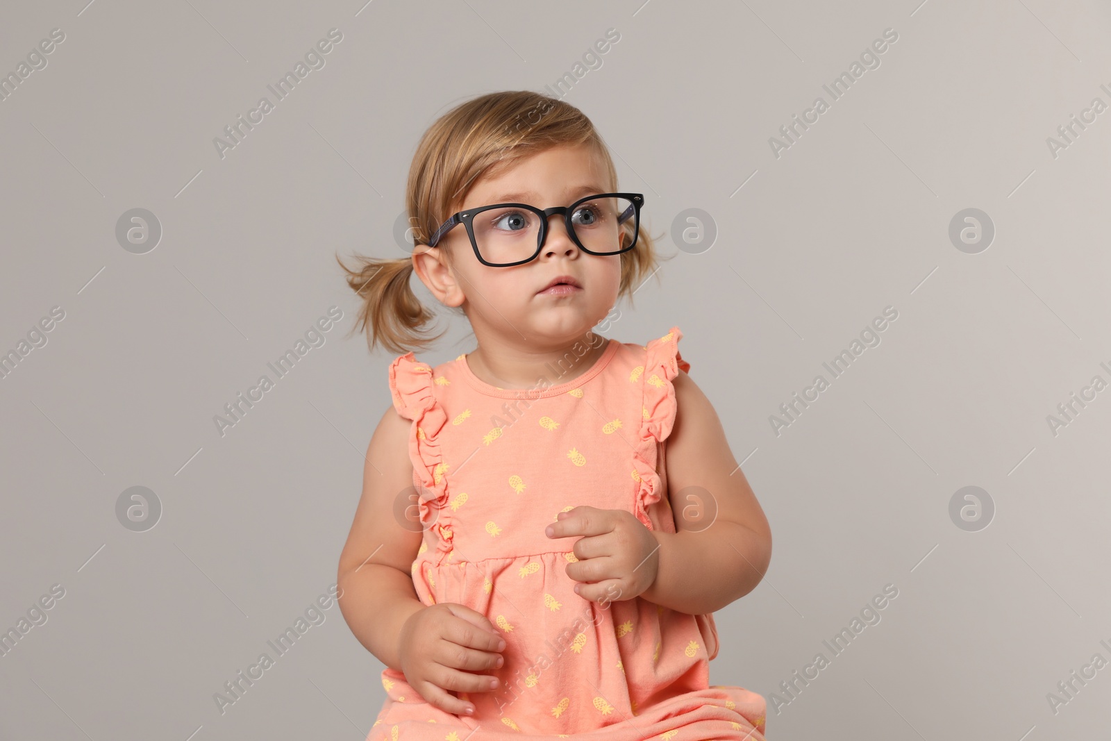 Photo of Cute little girl in glasses on light grey background