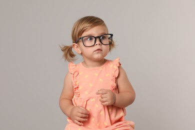 Cute little girl in glasses on light grey background