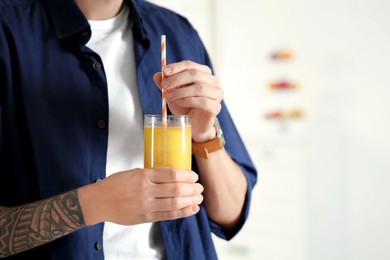 Man with delicious smoothie at home, closeup. Space for text