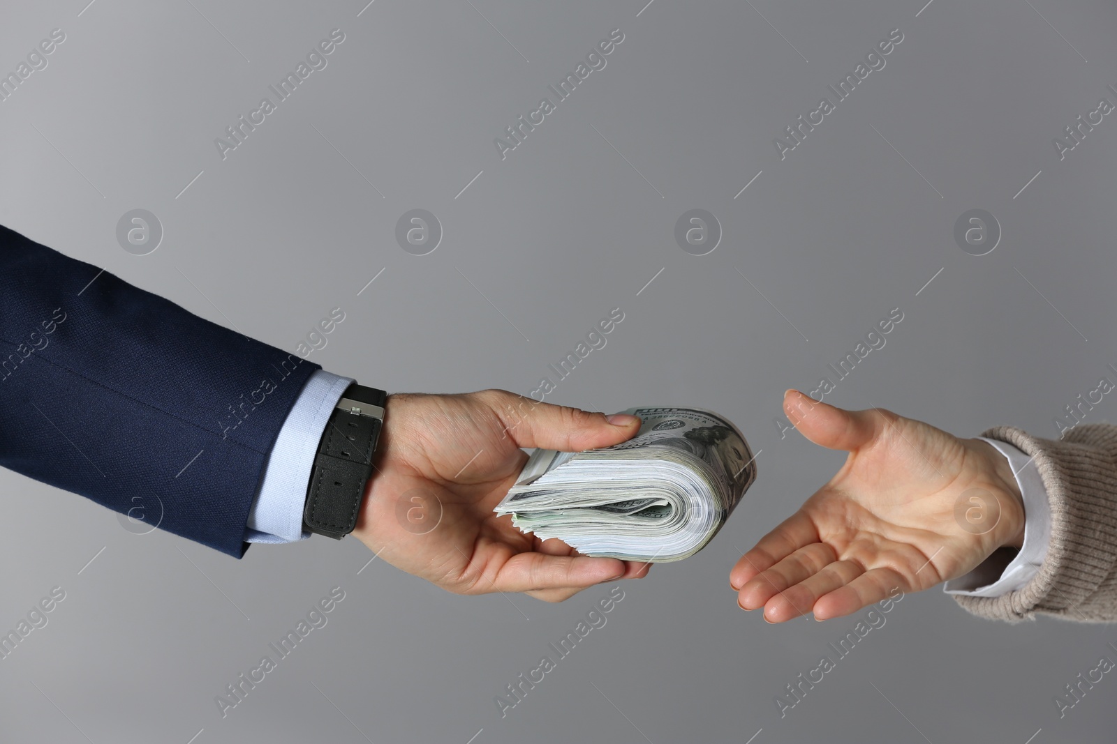 Photo of Man giving bribe money to woman on grey background, closeup