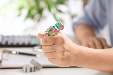 Woman squeezing colorful slime in office, closeup. Antistress toy