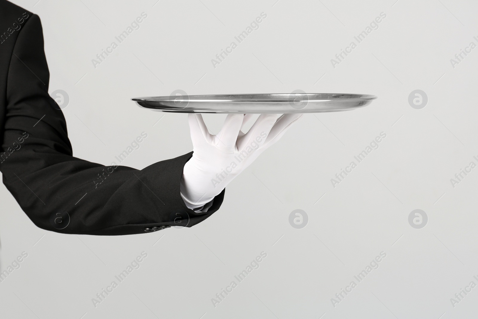 Photo of Waiter holding metal tray on light background