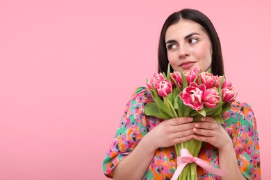 Happy young woman with beautiful bouquet on dusty pink background. Space for text