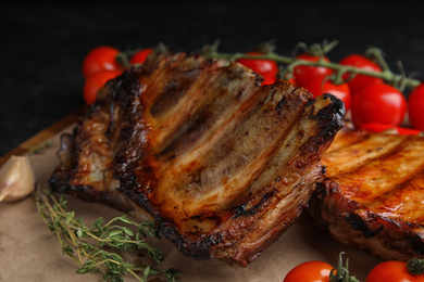 Photo of Tasty grilled ribs with tomatoes on table, closeup