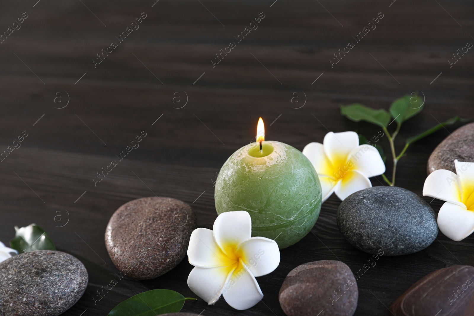 Photo of Composition with spa stones, flowers and candle on wooden background. Space for text