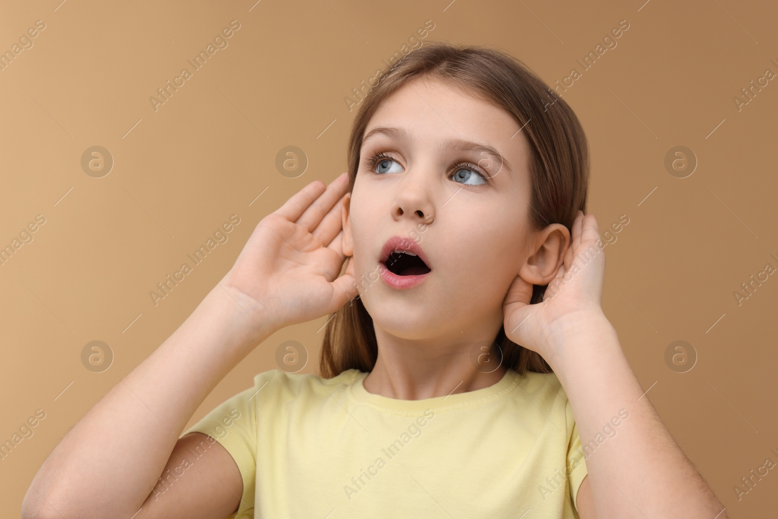 Photo of Little girl with hearing problem on pale brown background