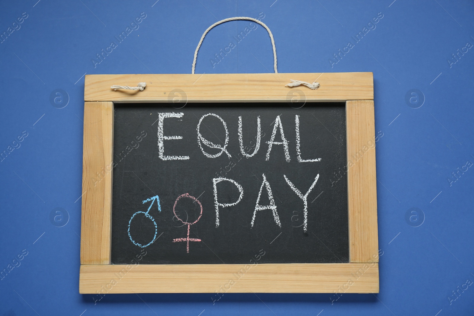 Photo of Blackboard with words Equal Pay and gender symbols on blue background, top view