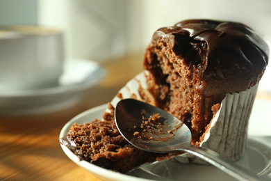 Photo of Cup of fresh aromatic coffee and cupcake at table in cafe