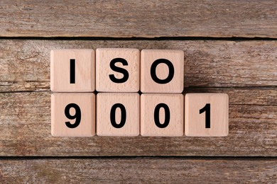 Photo of International Organization for Standardization. Cubes with abbreviation ISO 9001 on wooden table, top view
