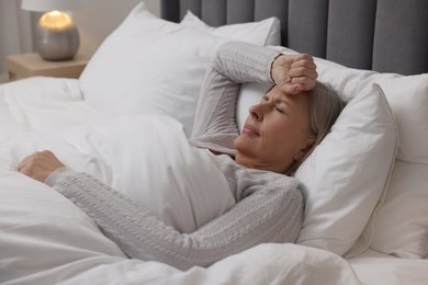 Photo of Menopause. Woman suffering from headache in bed