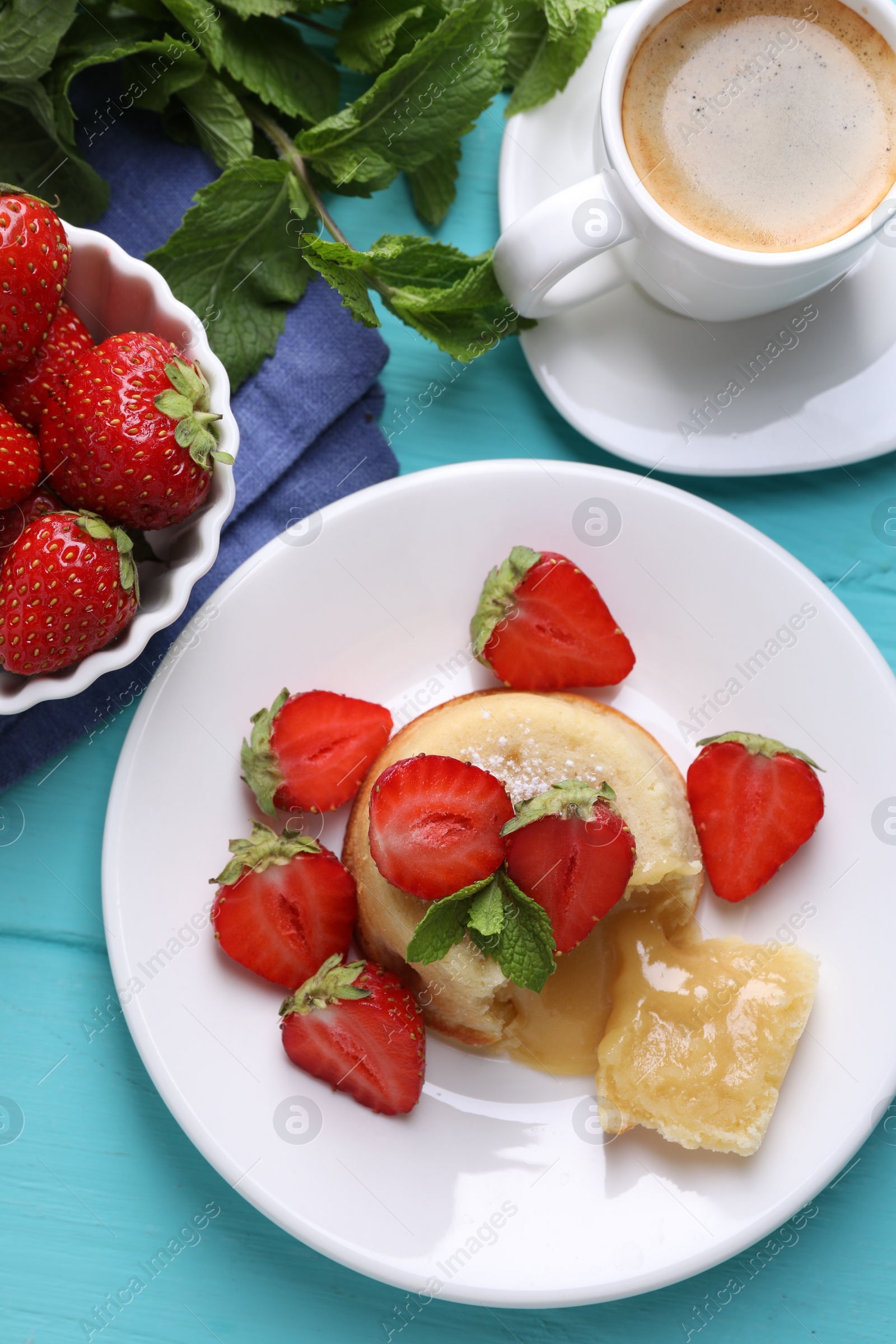 Photo of Tasty vanilla fondant with white chocolate, strawberries and cup of coffee on light blue wooden table, flat lay