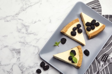 Photo of Pieces of delicious cheesecake with blackberries on white marble background, flat lay. Space for text