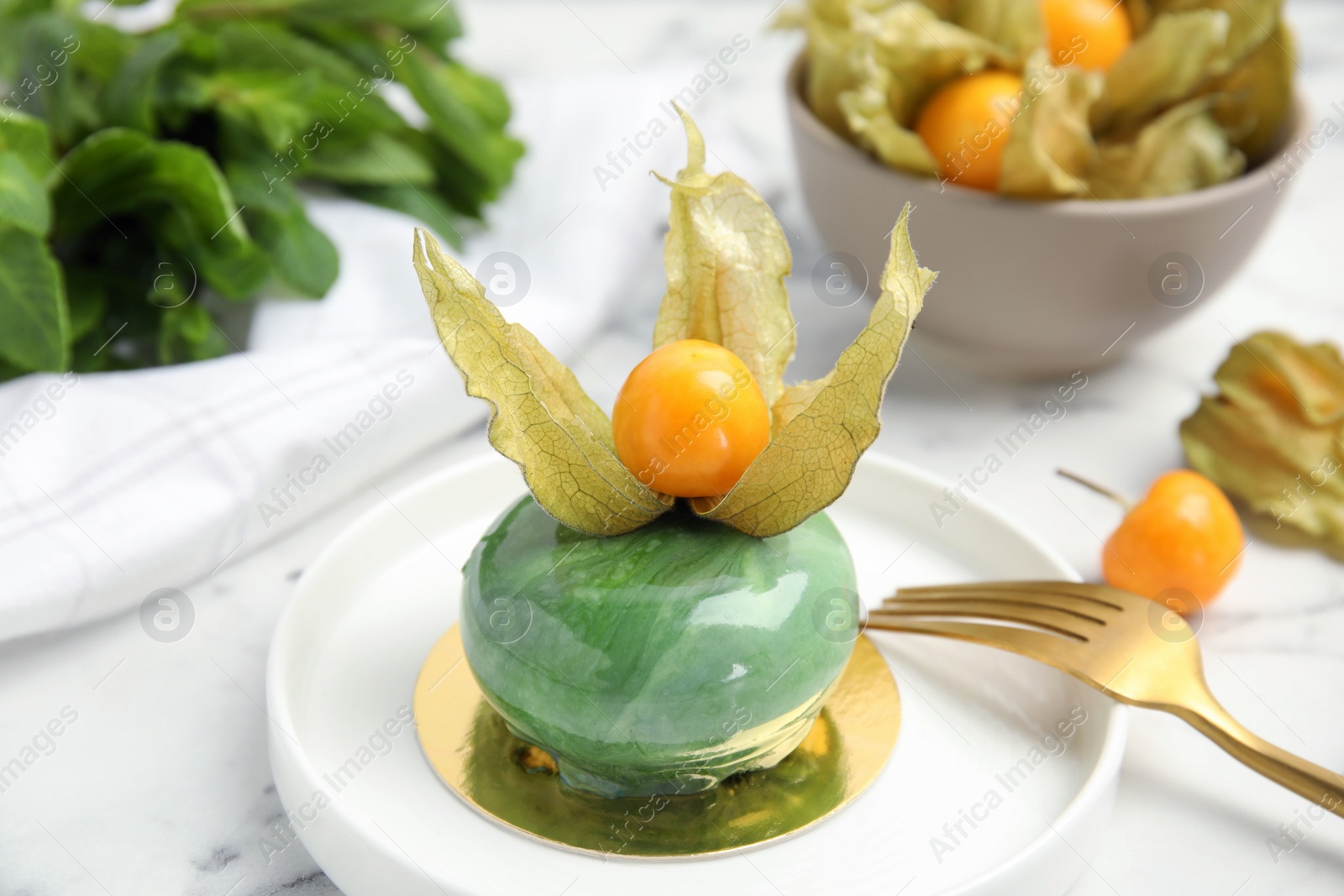Photo of Delicious mousse cake decorated with physalis fruit on white marble table