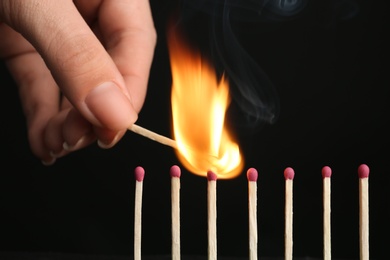 Photo of Woman igniting line of matches on black background, closeup. Space for text