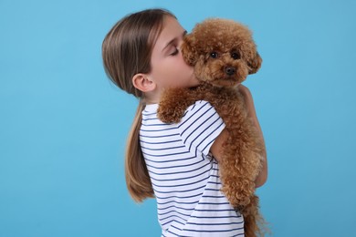 Photo of Little child with cute puppy on light blue background. Lovely pet