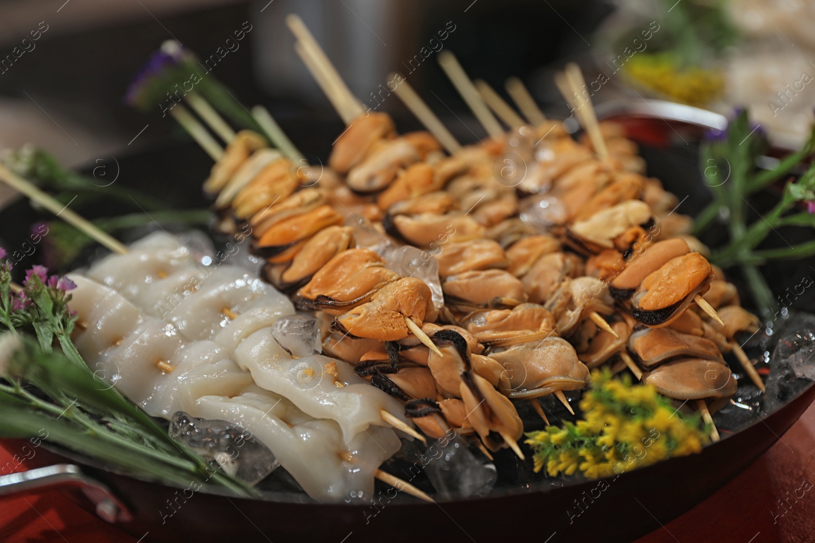 Photo of Seafood skewers served in dish with ice, closeup