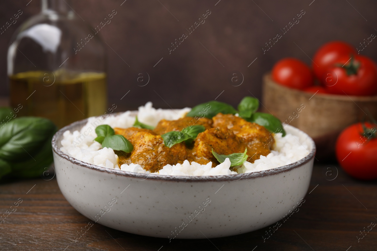 Photo of Delicious rice and chicken with curry sauce served on wooden table, closeup