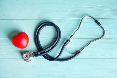 Photo of Stethoscope and red heart on wooden background, top view. Cardiology concept