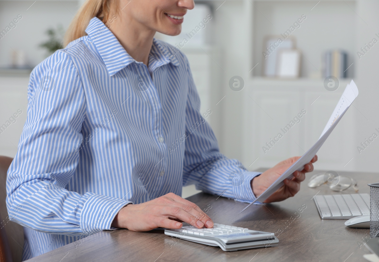 Photo of Professional accountant using calculator at wooden desk in office, closeup