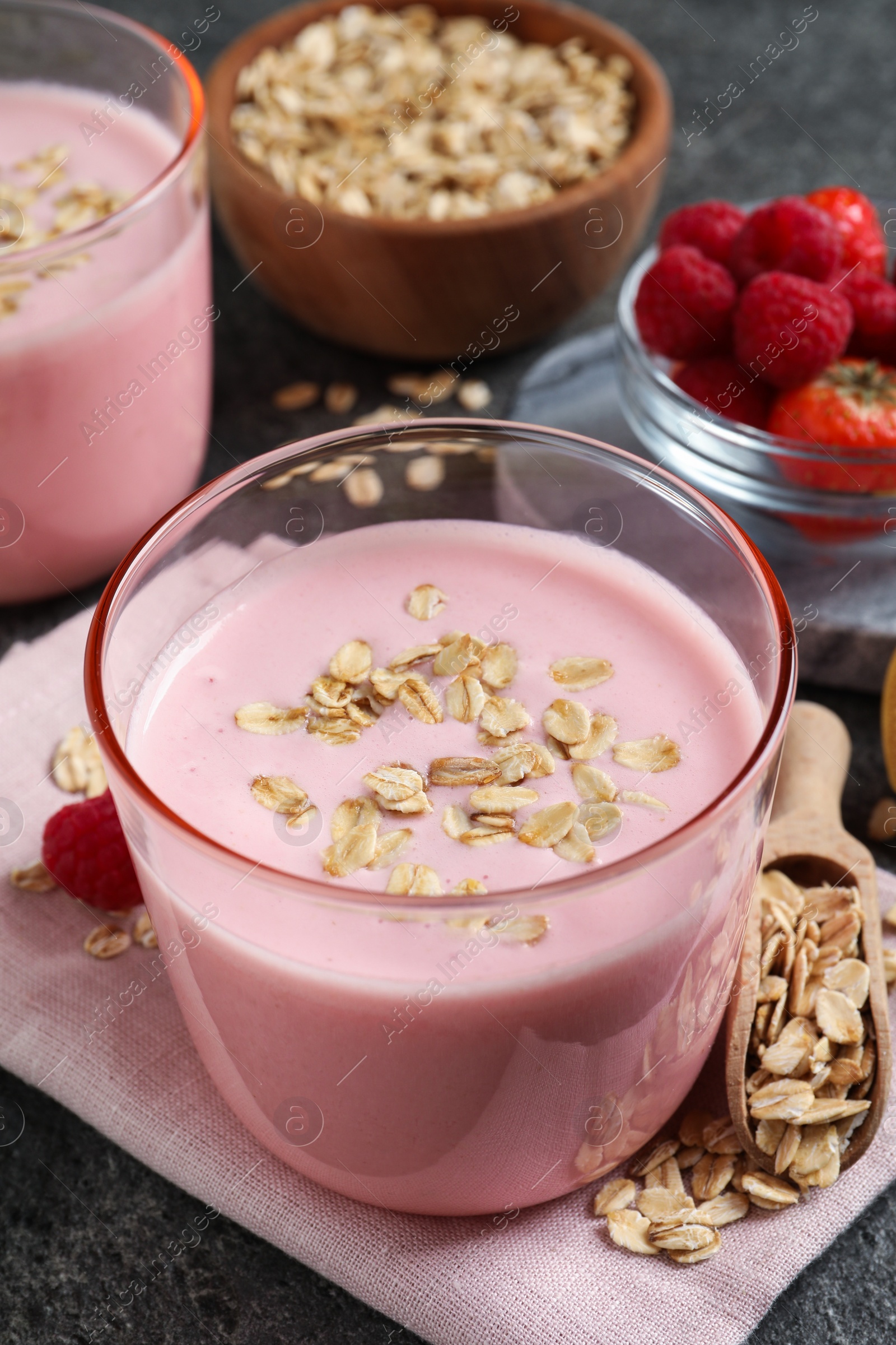 Photo of Glass of tasty berry smoothie with oatmeal on grey table, closeup