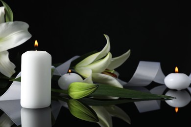 Photo of White lilies and burning candles on black mirror surface in darkness, closeup with space for text. Funeral symbols