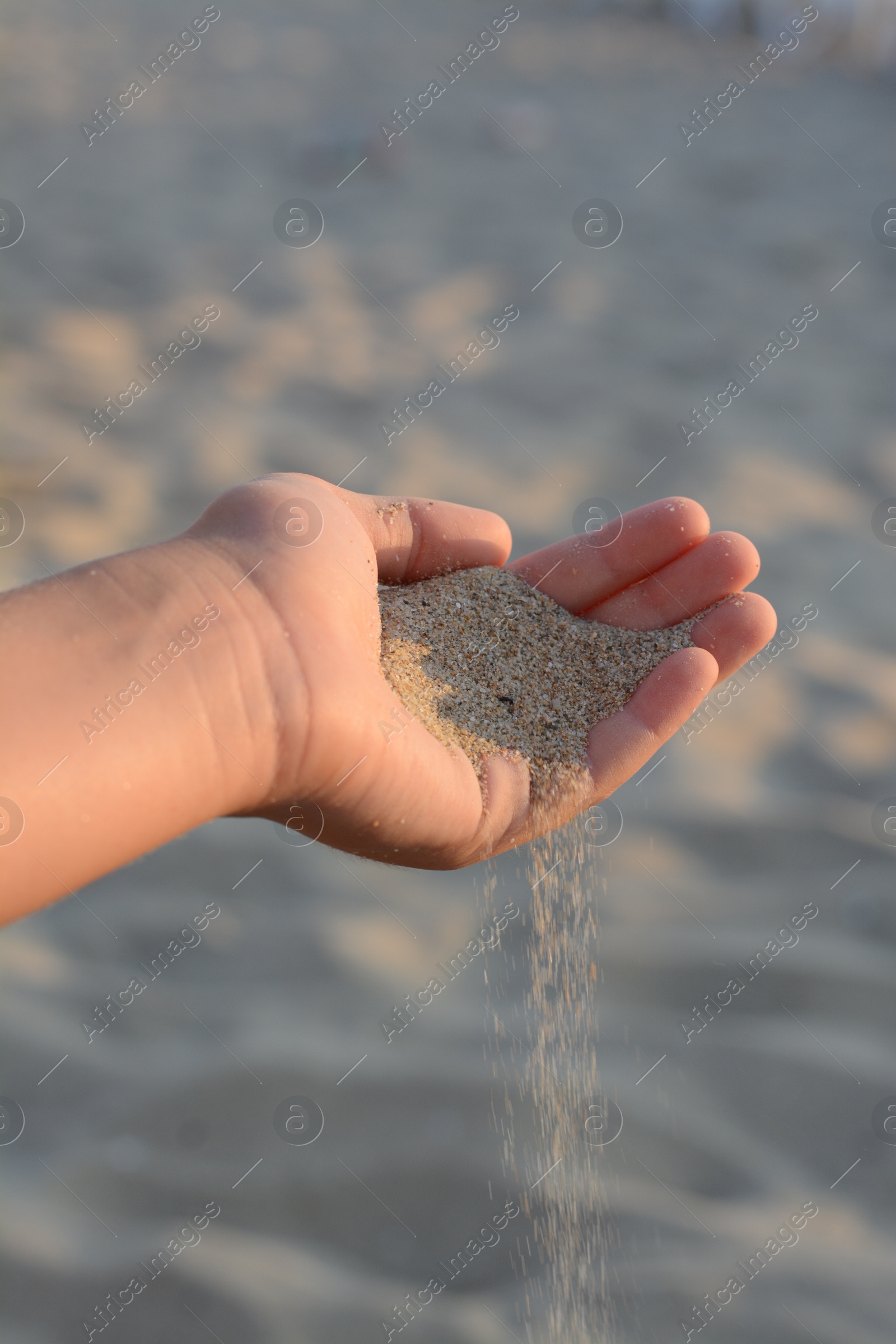 Photo of Girl pouring sand from hand outdoors, closeup. Fleeting time concept