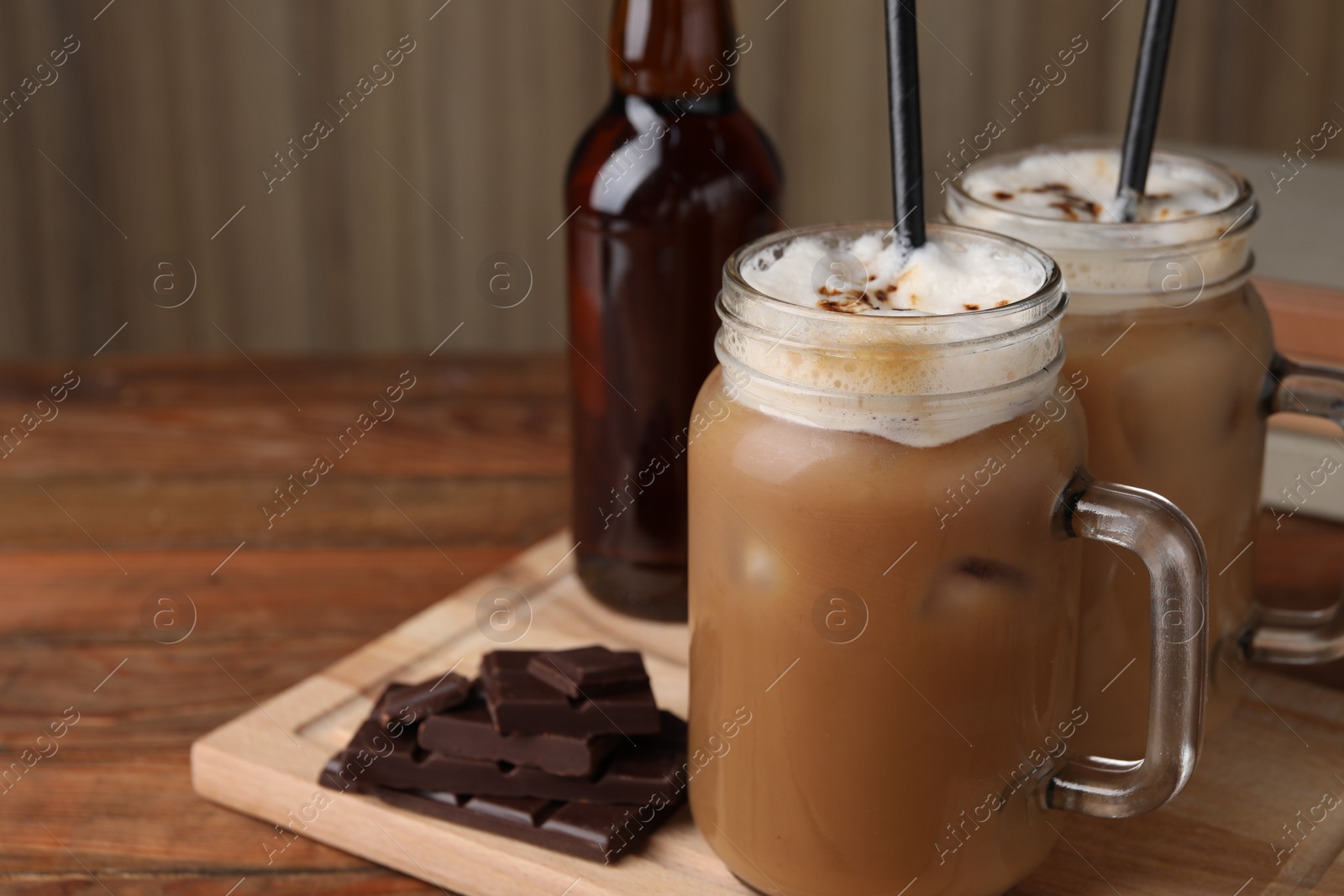 Photo of Delicious iced coffee with chocolate syrup on wooden table, space for text