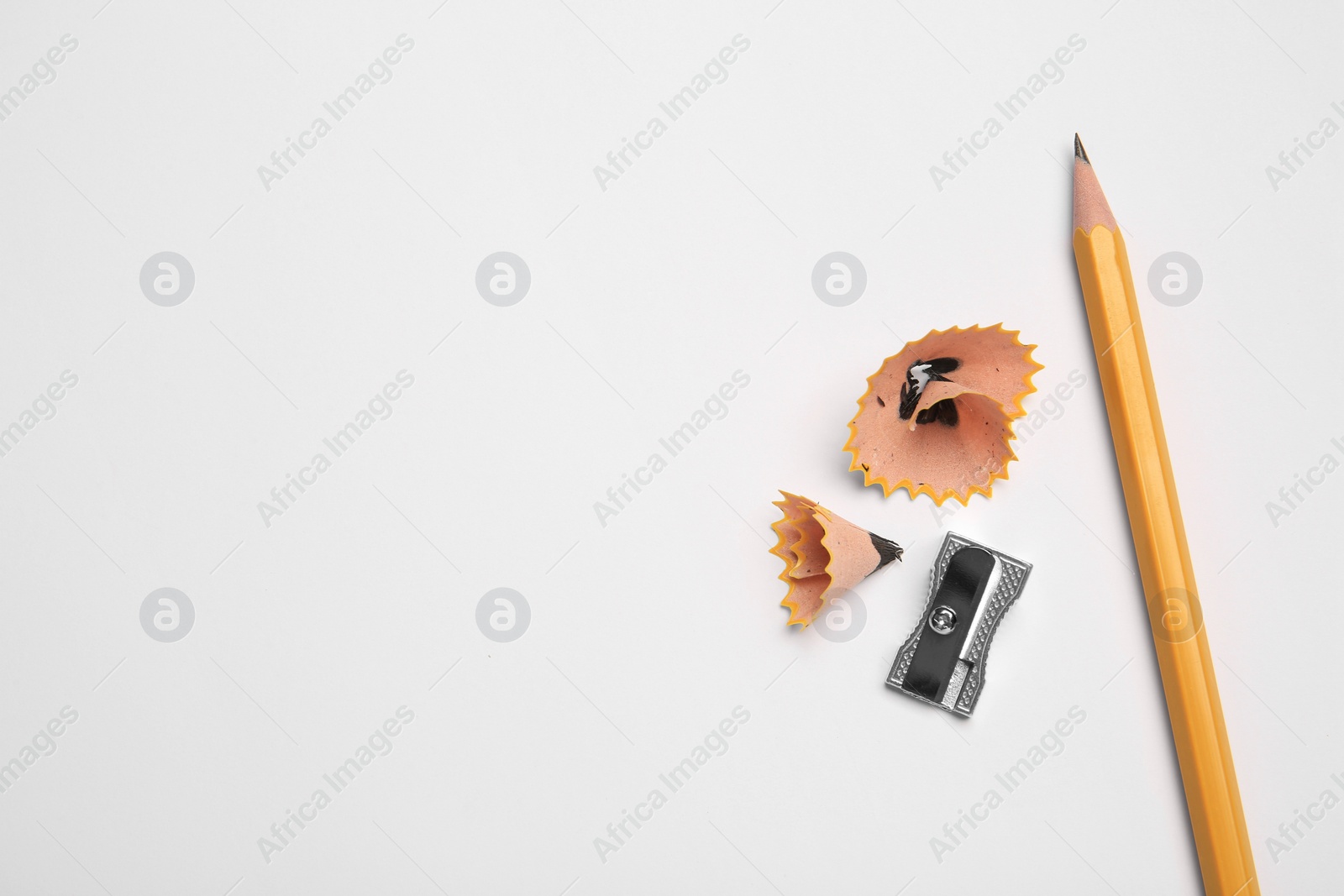 Photo of Graphite pencil, sharpener and shavings on white background, flat lay. Space for text