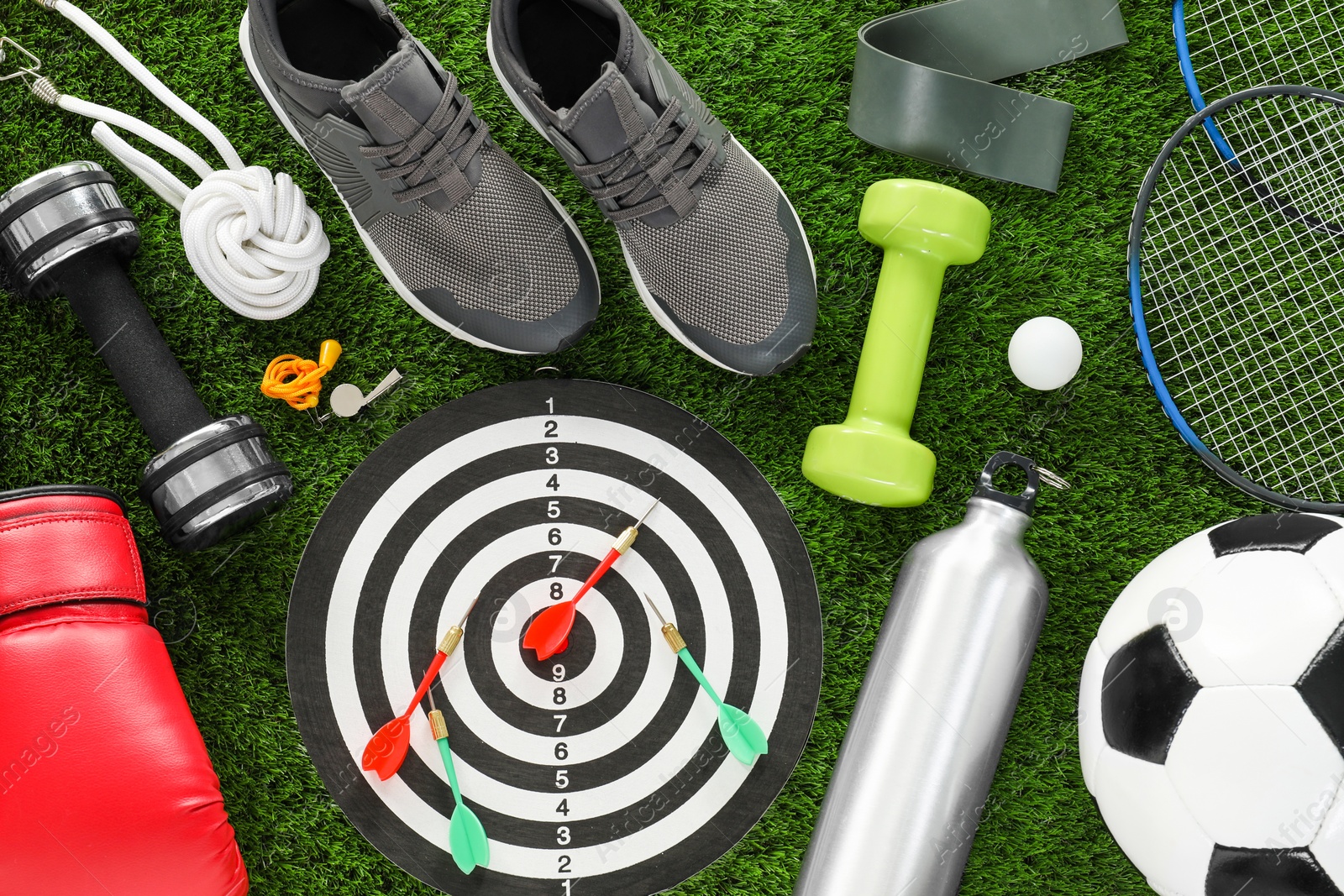 Photo of Different sport equipment and sneakers on green grass, flat lay