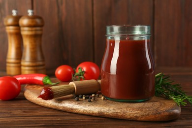 Tasty barbecue sauce in glass jar, brush and ingredients on wooden table, closeup