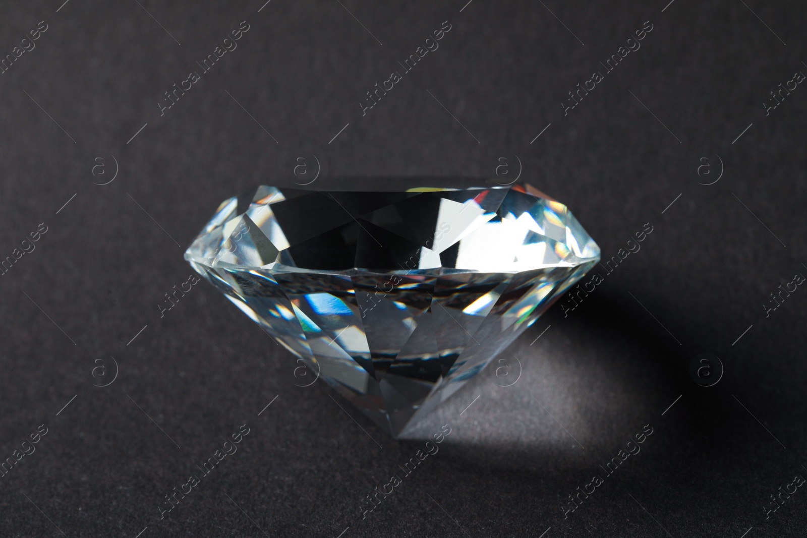 Photo of Beautiful dazzling diamond on dark background, closeup. Precious gemstone