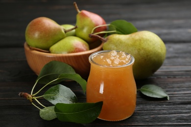 Delicious pear jam and fresh fruits on black wooden table