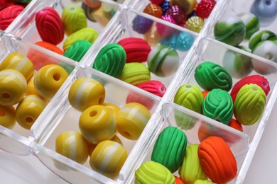 Photo of Plastic organizer with different beads on white background, closeup