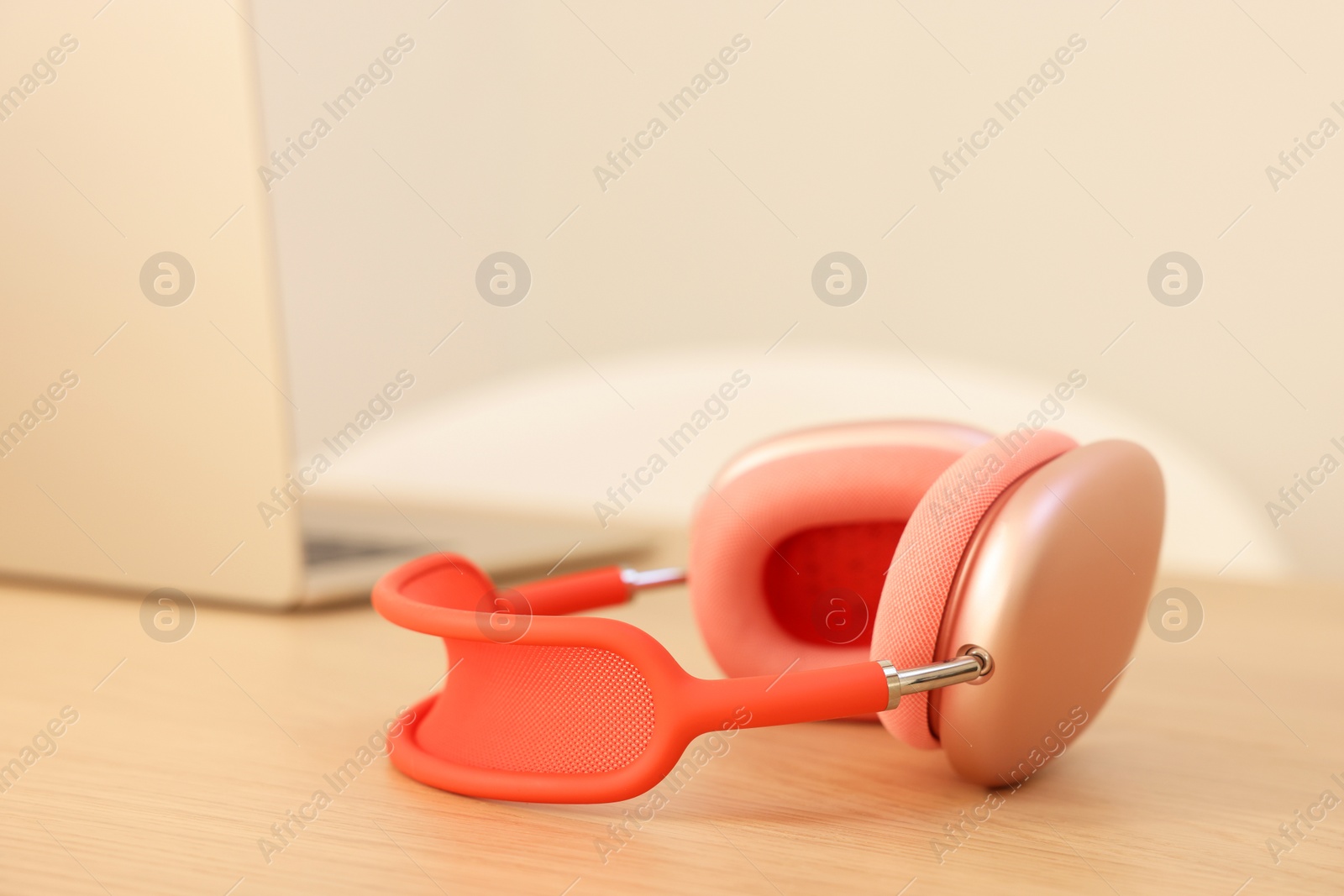 Photo of Modern headphones and laptop on wooden table