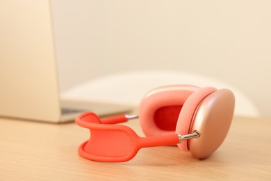 Photo of Modern headphones and laptop on wooden table