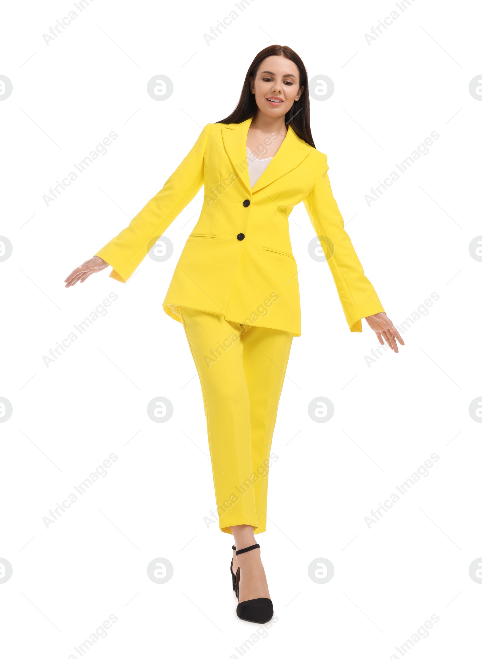 Photo of Beautiful businesswoman in yellow suit walking on white background