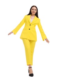 Beautiful businesswoman in yellow suit walking on white background