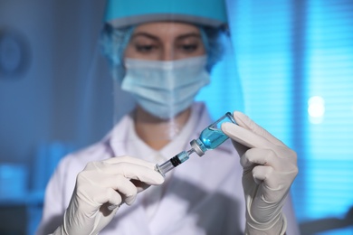 Doctor filling syringe with vaccine against Covid-19 in laboratory, focus on hands