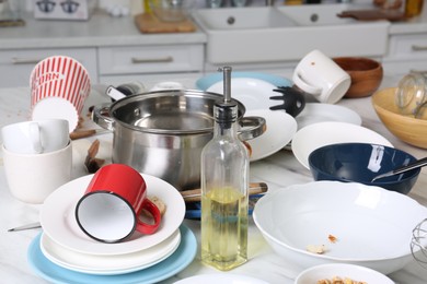 Many dirty utensils, dishware and food leftovers on white table. Mess in kitchen