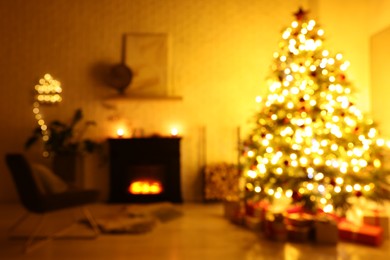 Photo of Beautiful Christmas tree near fireplace in room, blurred view. Interior design