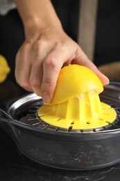 Photo of Woman squeezing lemon juice at black table, closeup