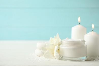 Photo of Spa composition with cream, candles and flowers on white table, space for text