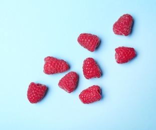 Flat lay composition with delicious ripe raspberries on blue background