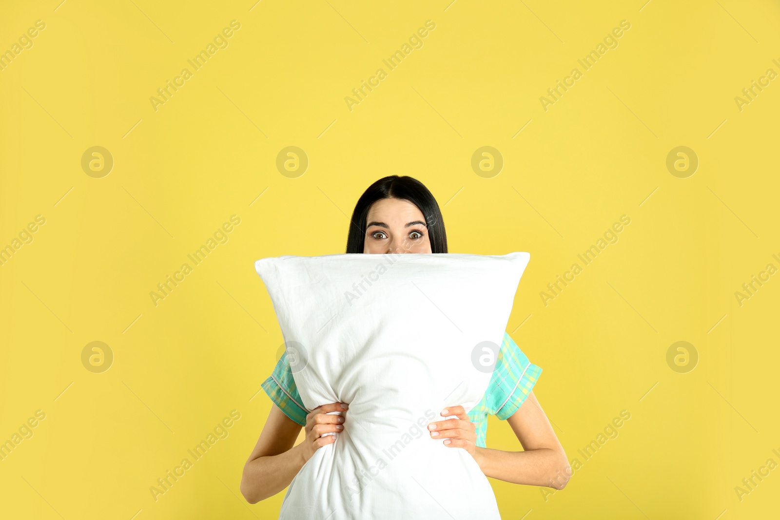 Photo of Young woman with pillow on yellow background